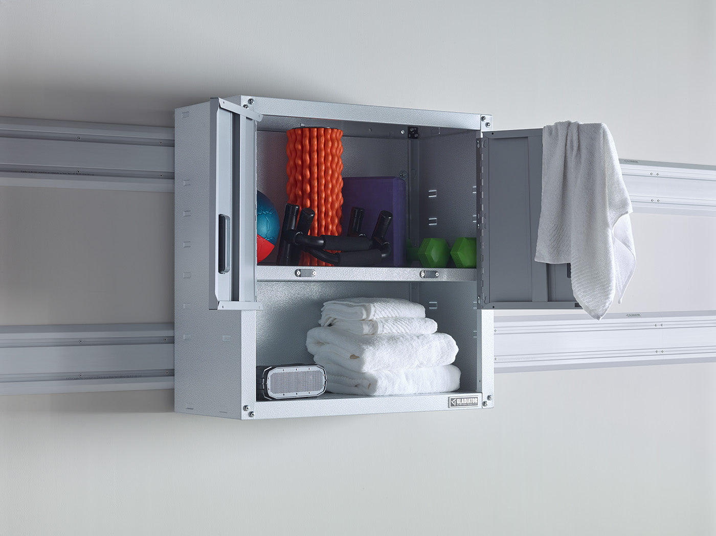 An open Gladiator brand wall cabinet filled with towels and other wellness equipment.