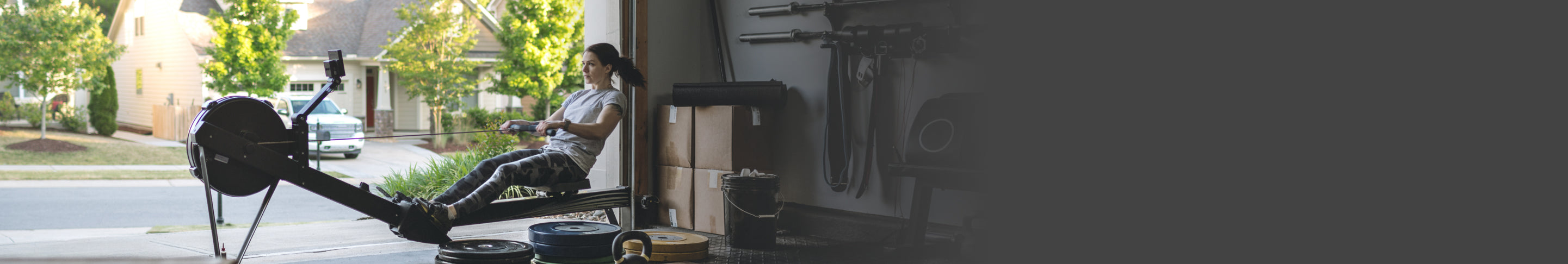 A person in their garage, exercising with weight-lifting equipment.