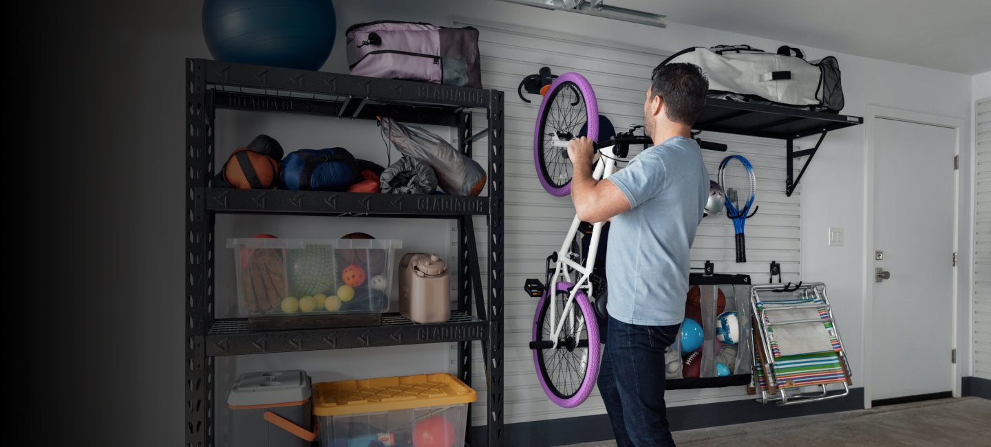 A person hanging a bike on a Gladiator® GearWall®.