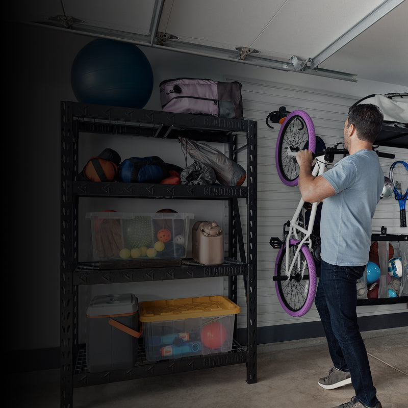 A person hanging a bike on a Gladiator® GearWall®.