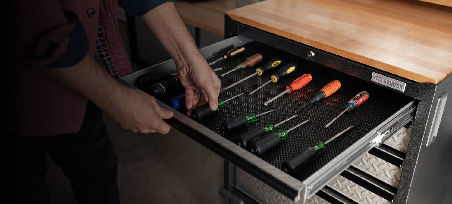 A person organizing tools into a Gladiator® storage cabinet