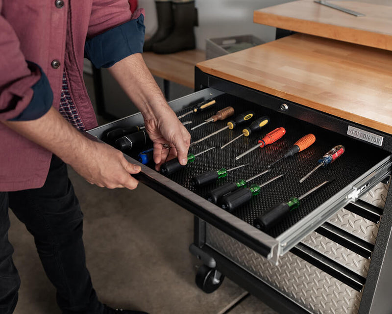 A person organizing tools into a Gladiator® storage cabinet