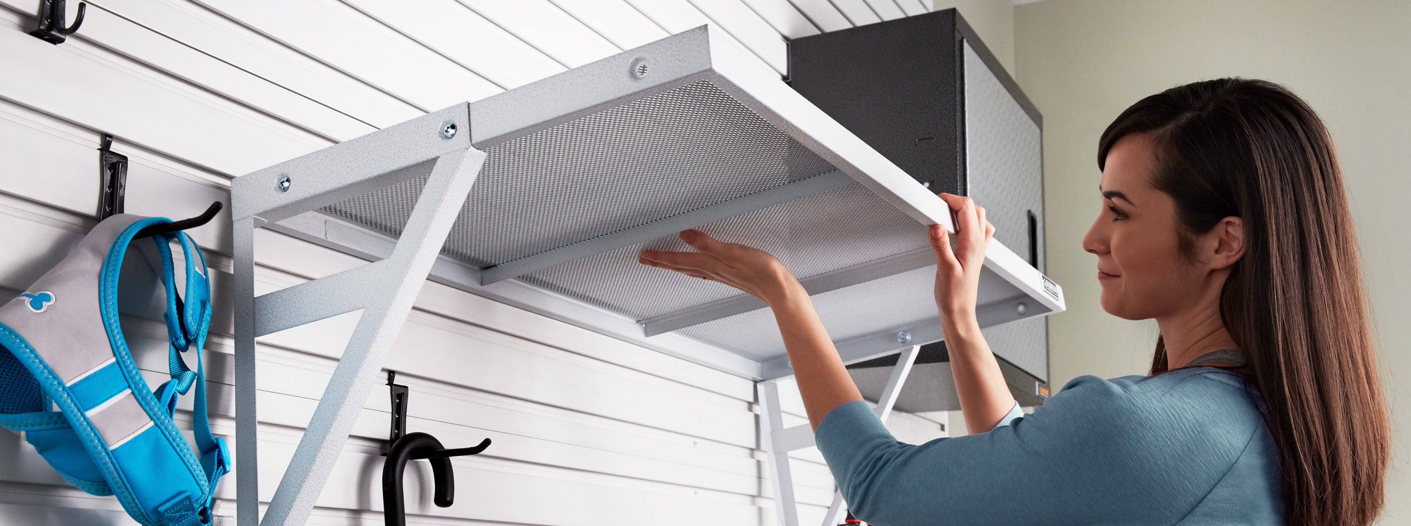 A person adjusting a Gladiator brand wall shelf.