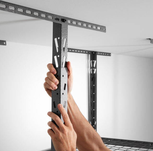 A person attaching a Gladiator brand overhead storage unit to the ceiling.