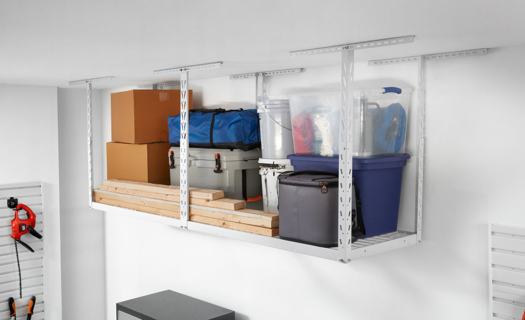 A Gladiator brand overhead storage unit installed near the wall, stacked with lumber, storage totes and footlockers.