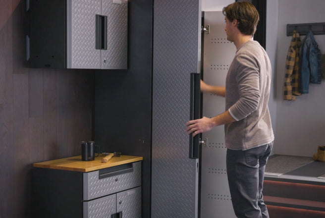 A man opening a cabinet in a garage.