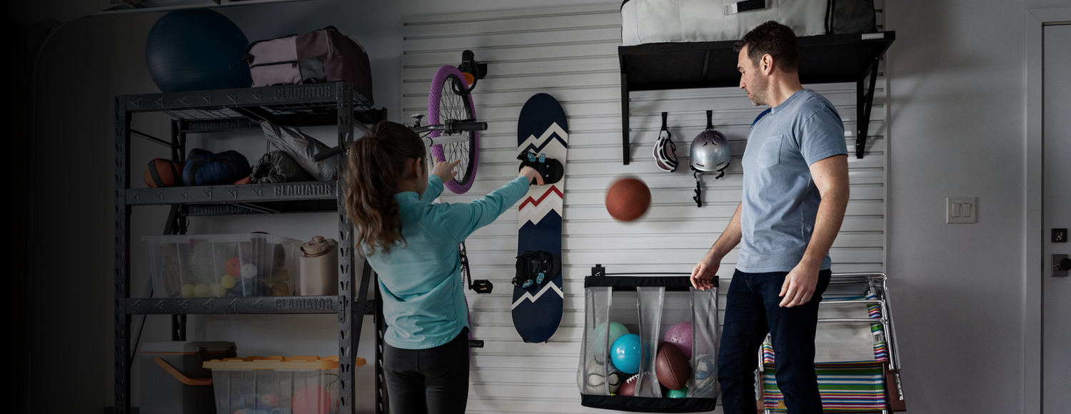 A dad and daughter organizing sports equipment in a garage