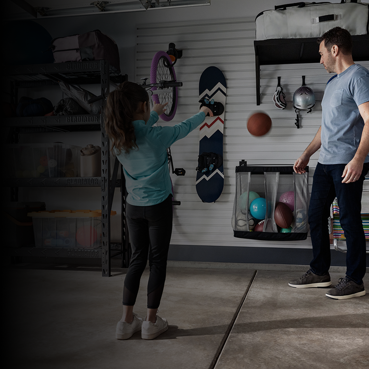A dad and daughter organizing sports equipment in a garage